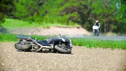 The motorcycle lies on the roadside, in the background the driver rides, slow Stock Footage 90319189