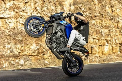 A motorcycle racer performs a difficult and dangerous stunt on his motorcycle Stock Photos