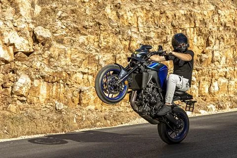 A motorcycle racer performs a difficult and dangerous stunt on his motorcycle Stock Photos