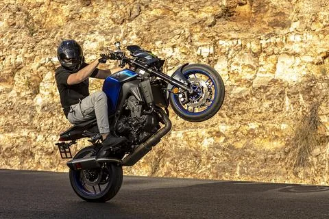 A motorcycle racer performs a difficult and dangerous stunt on his motorcycle Stock Photos