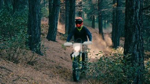 Motorcycle races through green trees in mountain forest on dirt extreme trail Видео 103565638