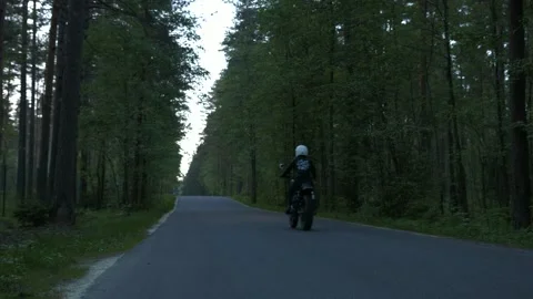 Motorcycle rides on the road in the forest Stock Footage 147554416