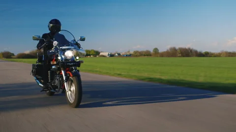 Motorcycle riding on a background of green field and blue sky Stock Footage 62351339