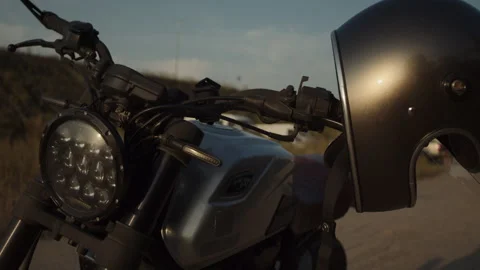 A motorcycle silver helmet hangs on the handlebars of a motorcycle waiting for t Stock Footage 253450071