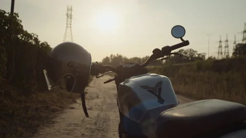 A motorcycle silver helmet hangs on the handlebars of a motorcycle waiting for t Stock Footage 253451366
