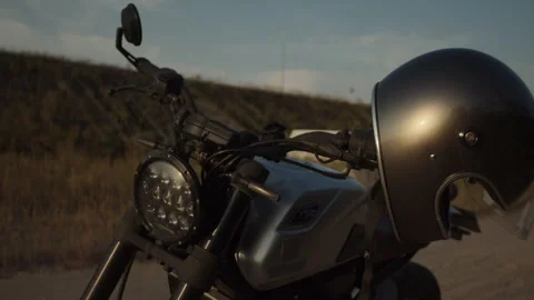 A motorcycle silver helmet hangs on the handlebars of a motorcycle waiting for t Stock Footage 253451636
