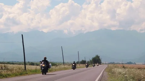Motorcycle tourists ride in the front of the cloudy mountains. Stock Footage 79968469