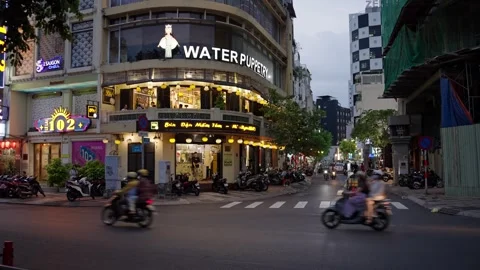Motorcycles navigate a busy intersection near the iconic Water Puppetry theater Stock Footage 332987563