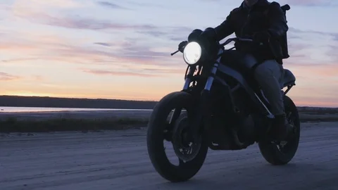 Motorcyclist driving his motorbike on the road after sunset Stock Footage