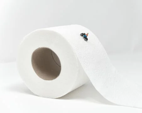 A motorcyclist rides up the side of a toilet roll - Tiny People Travelling Stock Photos