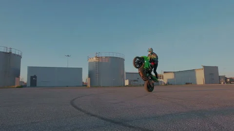 Motorcyclist training circle tricks on the back wheel on parking. Motorcycle Stock Footage 105048968