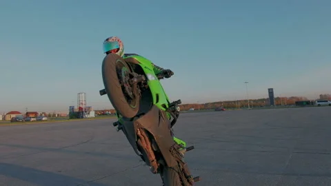 Motorcyclist training circle tricks outdoor in the sunset. Slow motion. Stock Footage 105048748