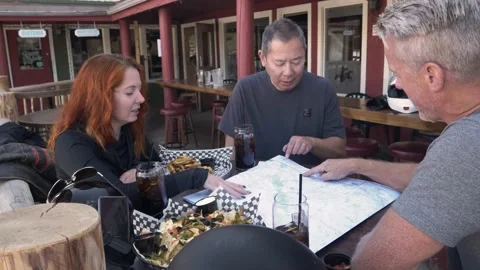Motorcyclists looking at map on table outside bar Vídeos de archivo 201939837