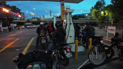 Motorcyclists queuing at PDV gas station in Caracas Venezuela evening Stock Footage 327607219