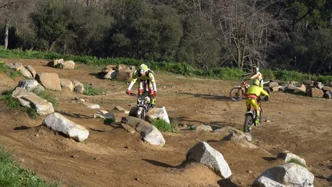 Motorcyclists take turns obstructing a track for a motorcycle trial Видео 126064607