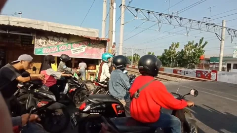 Motorcyclists wait for a train to pass behind a wooden barrier Stock Footage 281039663