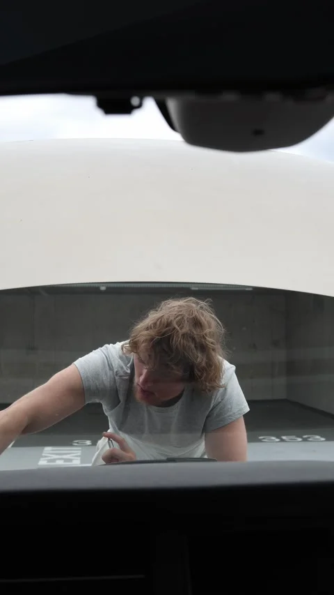 Motorist studies the engine and considers repair options beside the open hood Video stock 342918904
