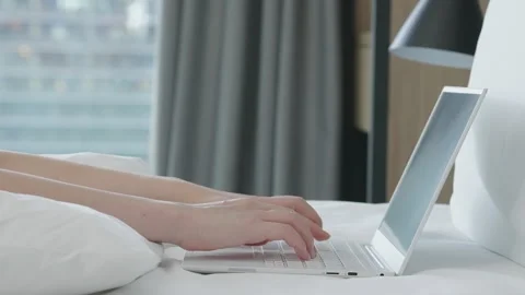 Motorized dolly shot of using laptop computer on bed in hotel room Stock Footage 194463930