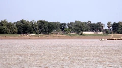  motorized dugout canoe pulling behind a large heap of bamboo poles down a river Video stock 113322892