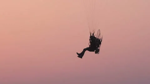 A motorized paraglider flies in the evening sky Stock Footage 158792704