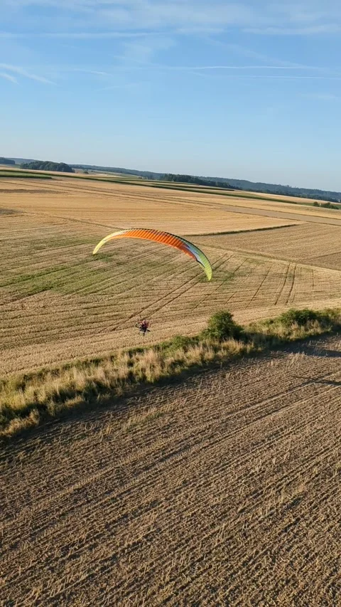 Motorized paragliding pilot flying low above ground enjoying powered flight Video stock 334683991