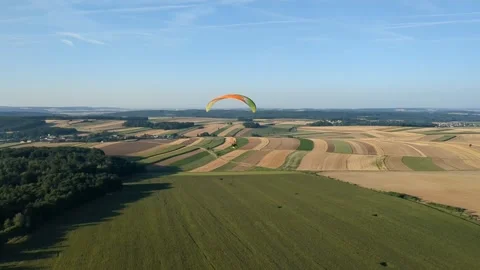 Motorized paragliding pilot flying low above ground enjoying powered flight 库存影片 334684020