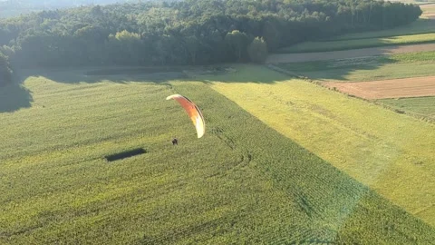 Motorized paragliding pilot flying low above ground enjoying powered flight 库存影片 334684026