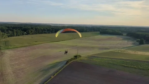 Motorized paragliding pilot flying low above ground enjoying powered flight 库存影片 334684027