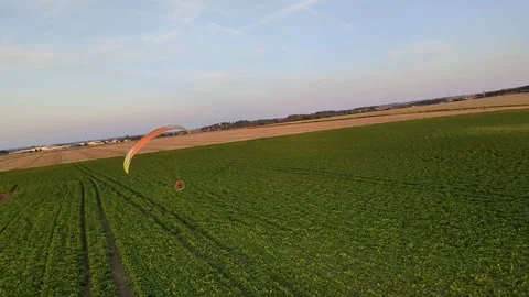 Motorized paragliding pilot flying low above ground enjoying powered flight 库存影片 334684045
