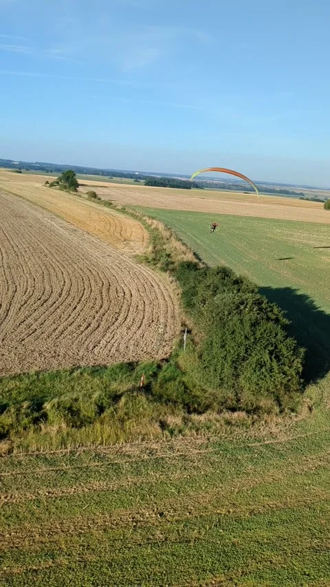 Motorized paragliding pilot flying low above ground enjoying powered flight 库存影片 334685809