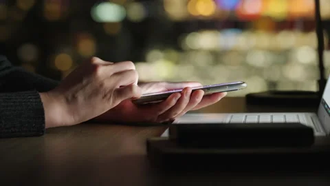 Motorized rising shot of using smartphone at night, out focus city background Stock Footage 194613373
