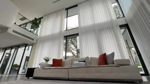 Motorized Sheer Curtains Opening to Leafy Garden in Double-Height Living Room Stock Footage 343906946