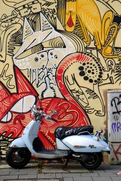 Motorroller Buntes Graffito an einer Hauswand mit parkendem Motorroller. H... Stock Photos