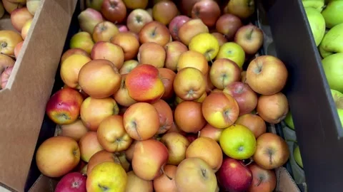 A mound of large red coloured apples in boxes is displayed in the window of the Stock Footage 316372410