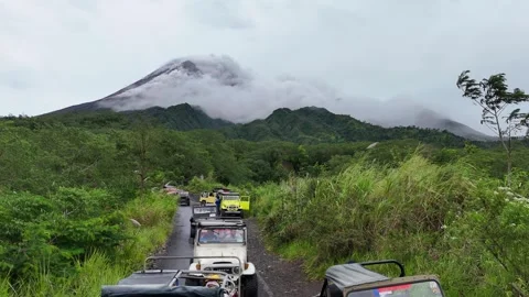Mount Merapi erupting from Kaliadem lava tour area with off-road jeeps Stock Footage 332532903