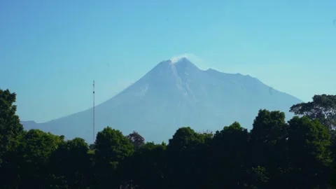 Mount Merapi rises beyond a dark green treeline near Prambanan Temple under.. Vídeo Stock 341544091