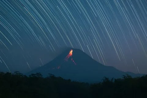 Mount Merapi volcano eruption glowing lava flow at night with star trail ba.. Fotos Stock