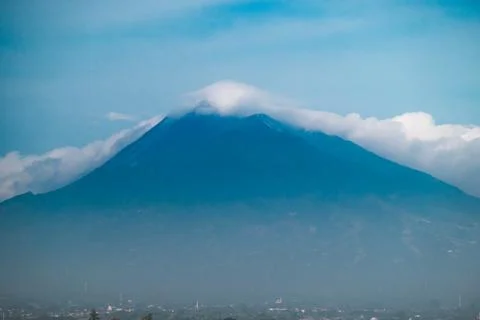 Mount Merbabu Volcano with Cloud Covered Summit Rising Above Distant City U.. Stock Photos