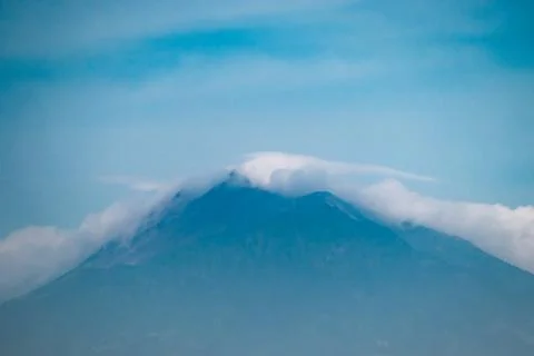 Mount Merbabu Volcano Covered by Cloud Cap and Misty Atmosphere Under Blue .. Stock Photos