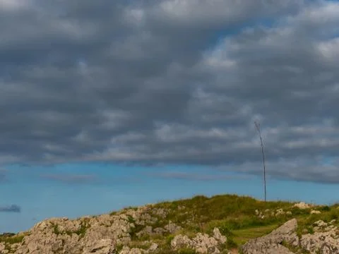 Mount with rocks and a tree under a cloudy sky Stock Photos
