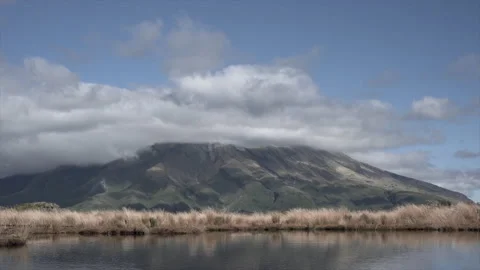 Mount taranaki with clouds around it with vegetation and sea, new zealand Stock Footage 220863927