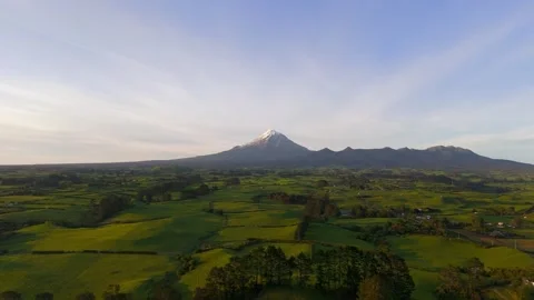 Mount Taranaki volcano over green farmland at sunrise Video stock 330886524