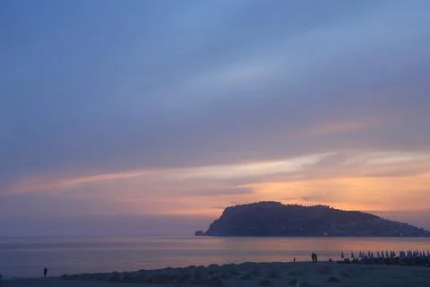 Mountain and deserted beach in the rays of the setting sun in Alanya, Turke.. Stock Photos