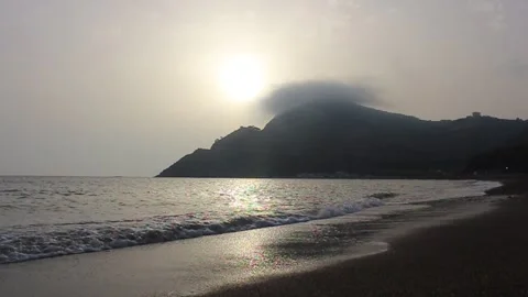 A mountain on the beach with clouds above it in the early morning Stock Footage 136943627