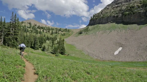 A mountain biker bikes away from camera with mountains in background in Idaho Stock Footage 36312200