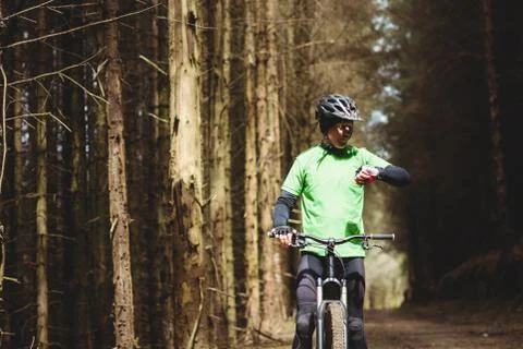 Mountain biker checking time while riding in forest Stock Photos