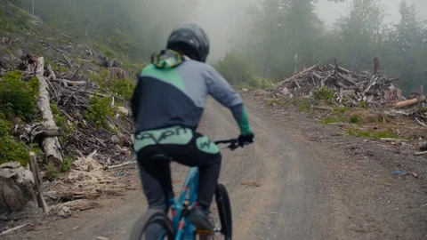 Mountain Biker Climbs up misty fire road Stock Footage 89926025