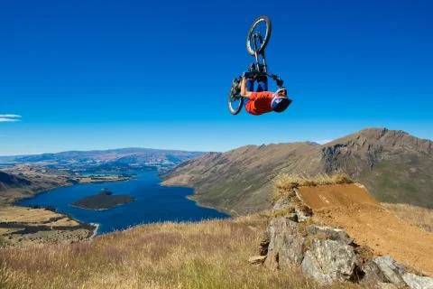 Mountain biker does backflip above lake. High Resolution Photo. Stock Photos