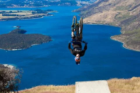 Mountain biker does backflip above lake. High Resolution Photo. Stock Photos