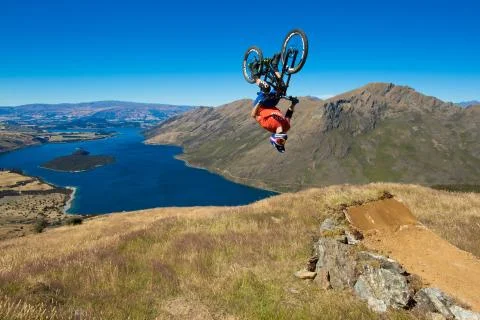 Mountain biker does backflip above lake. High Resolution Photo. Stock Photos